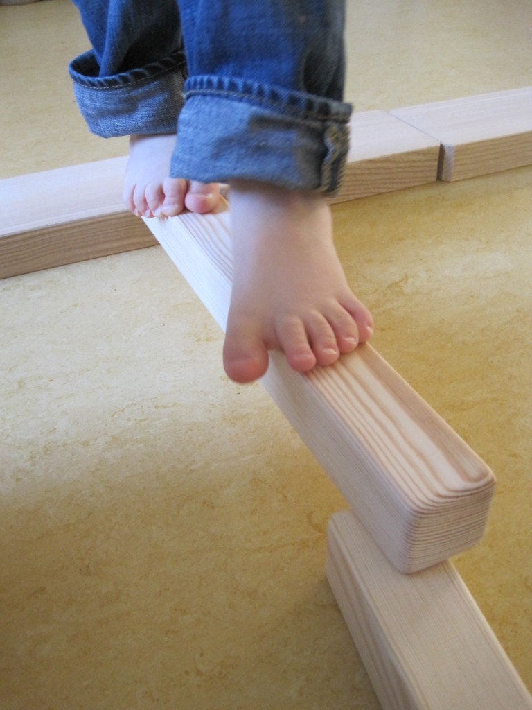 Nackte Kinderfüße balancieren auf einem schmalen Holzbalken