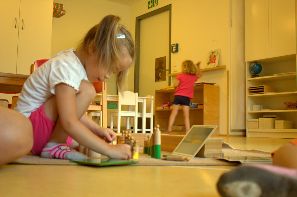 Mädchen arbeitet konzentriert auf dem Boden mit Montessori-Material